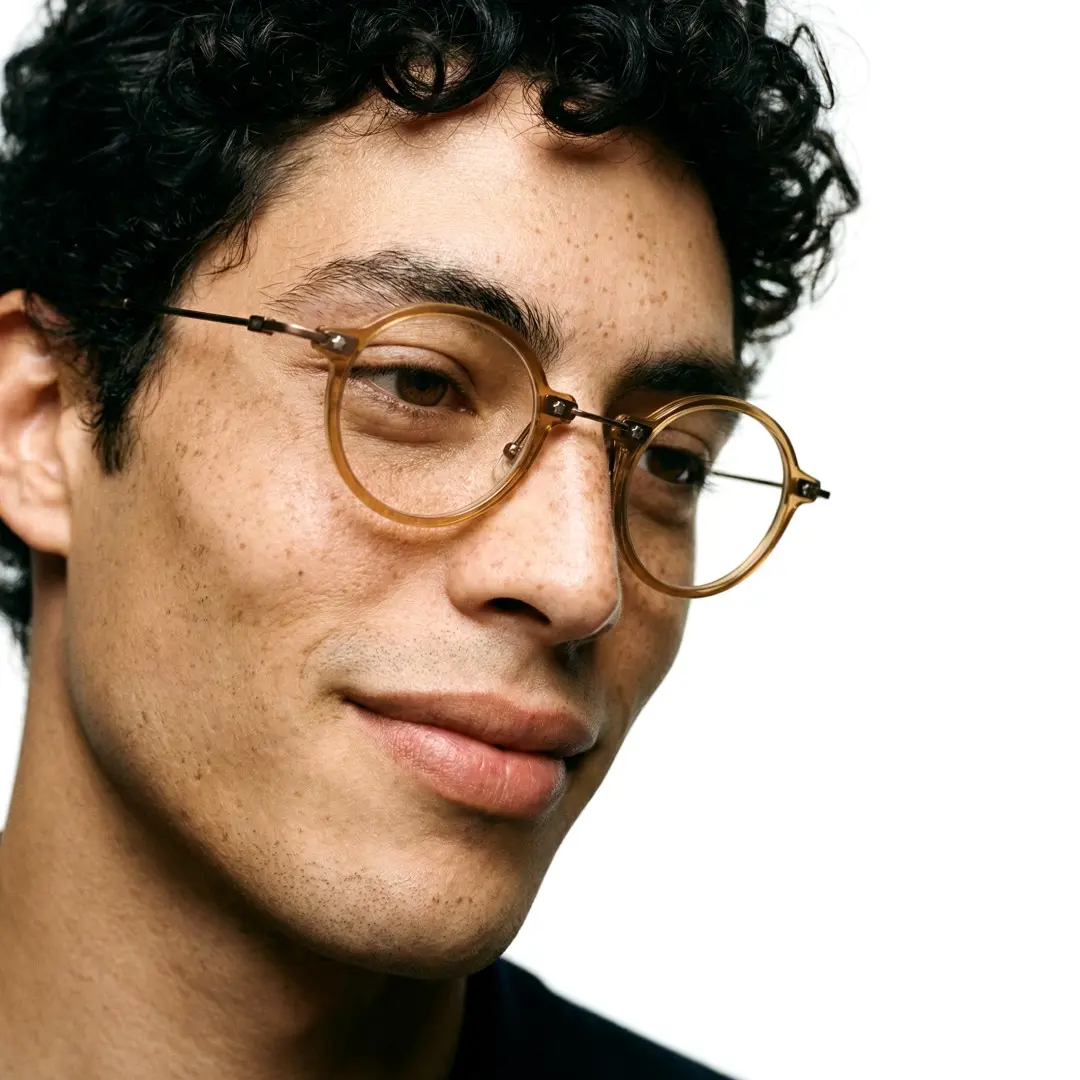 Profile view of male wearing steampunk gold round eyeglasses, natural smile, RA0092309