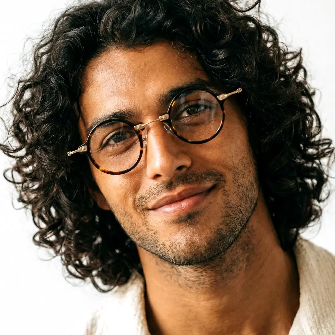 Front view of male wearing tortoise round eyeglasses, smiling, RA0092309