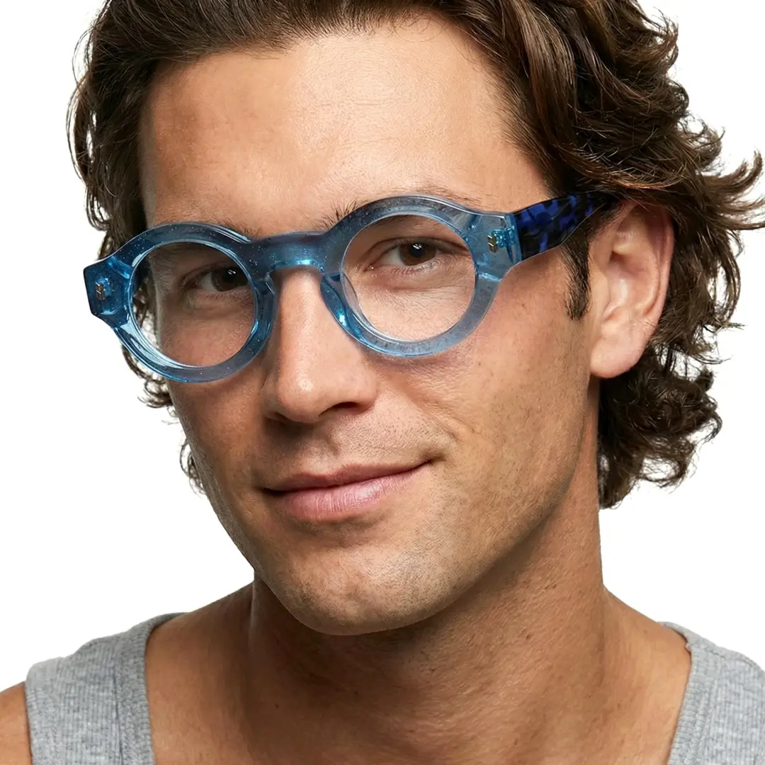 Three-quarter view of male wearing blue round eyeglasses, smiling, RA0110507