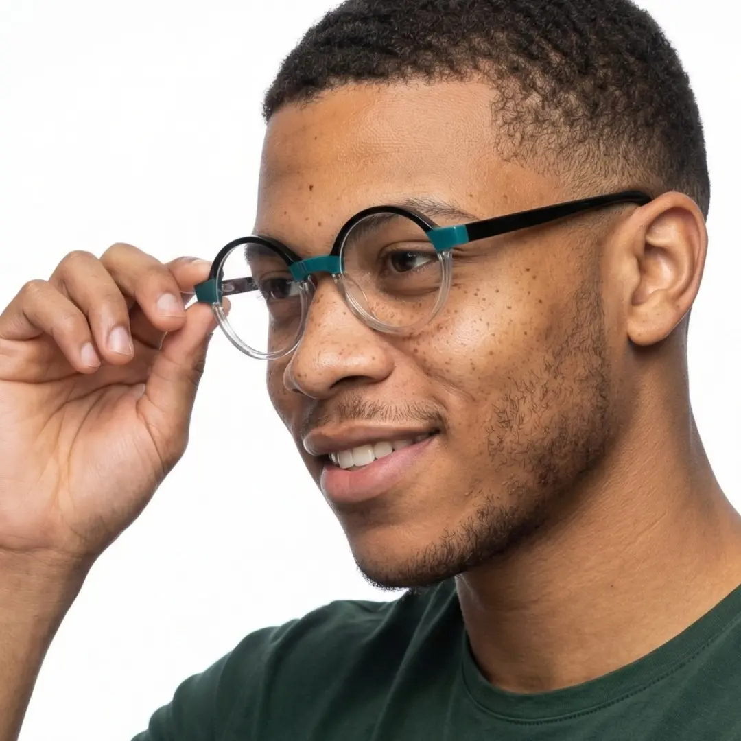 Profile view of male wearing two-tone round eyeglasses, adjusting glasses, smiling, RA0112309