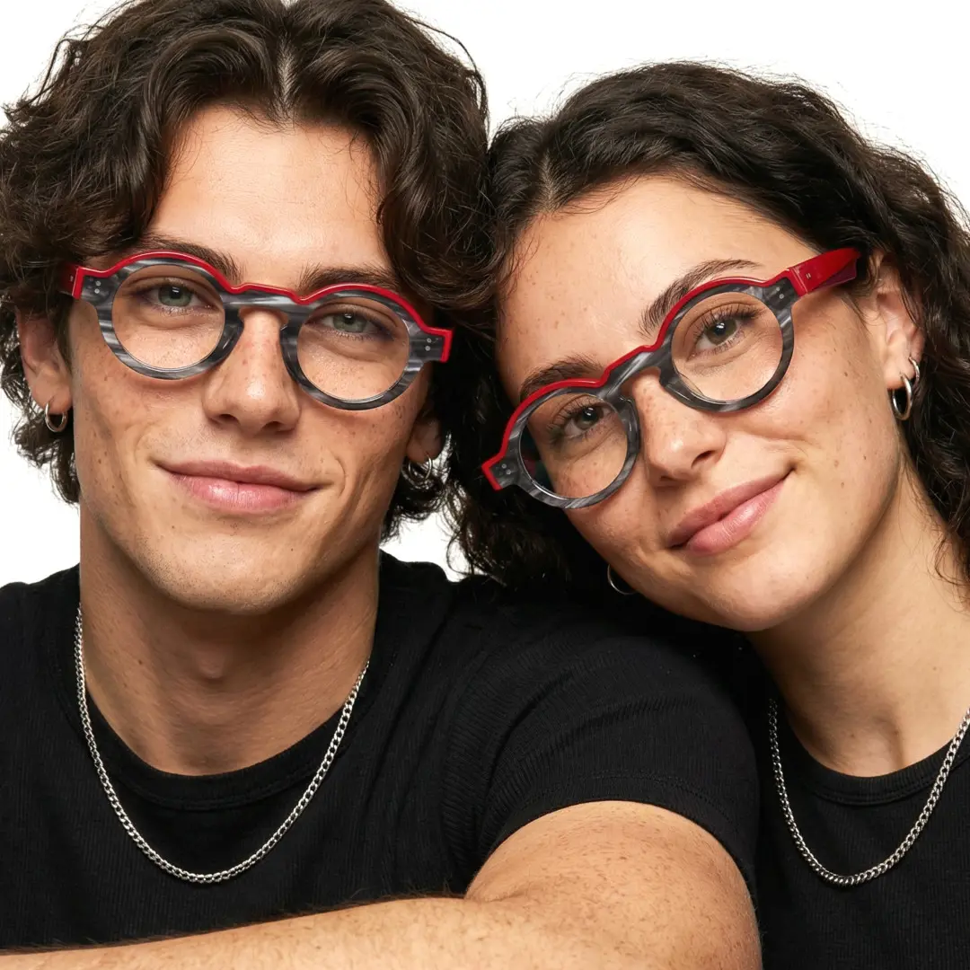 Front view of couple wearing colorful black round eyeglasses, smiling, RA0152406