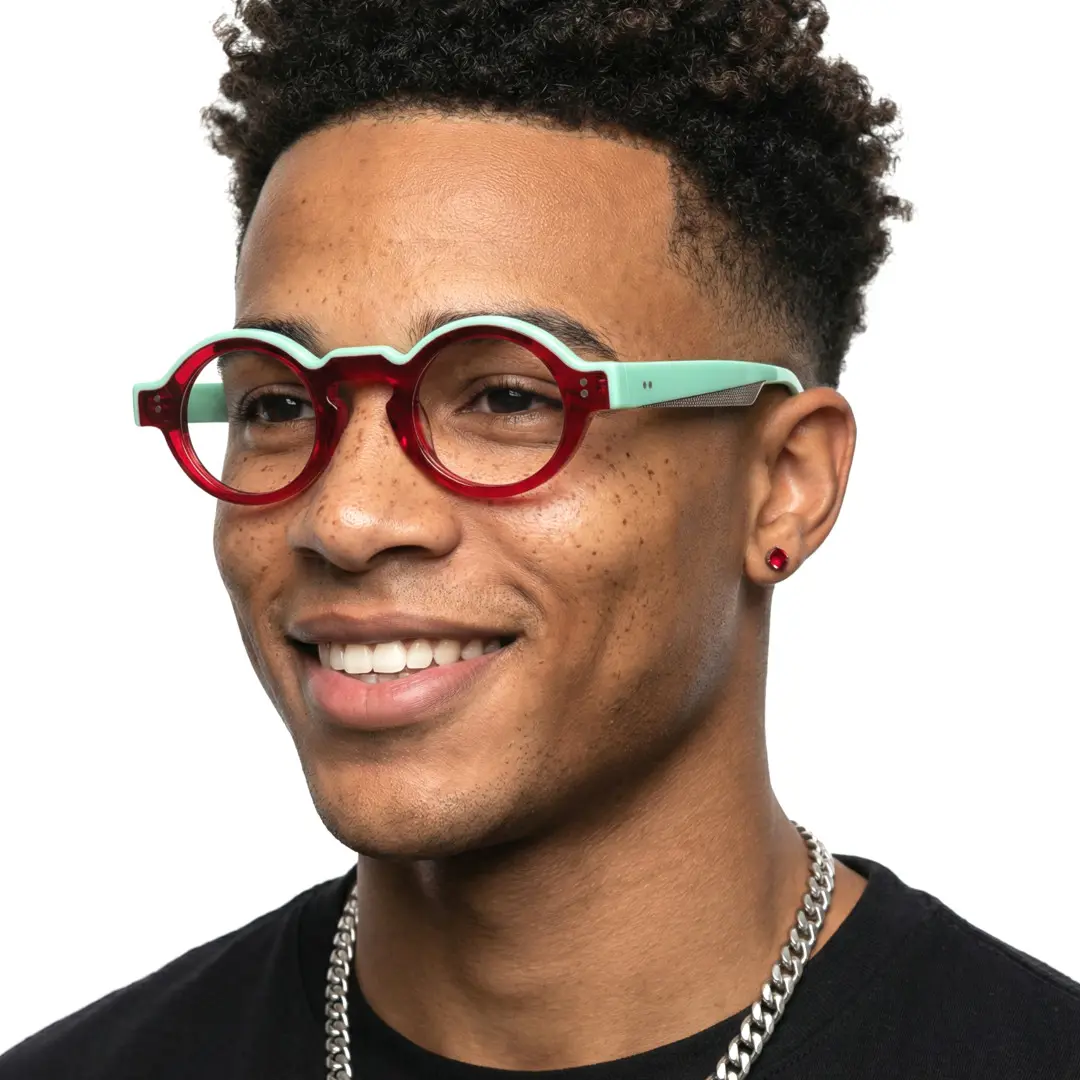 Three-quarter view of male wearing colorful red round eyeglasses, smiling, RA0152406