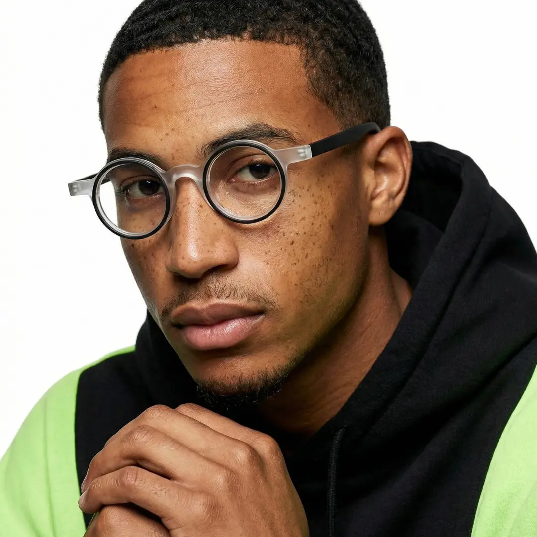 Slightly angled view of male wearing black round eyeglasses, neutral expression, RA0162406