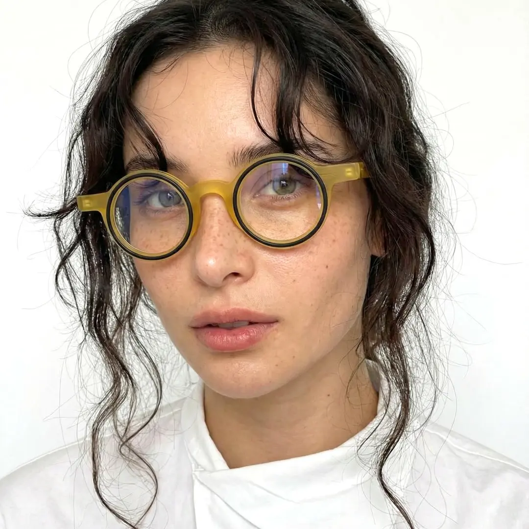 Slightly angled view of female wearing yellow round eyeglasses, natural expression, RA0162406