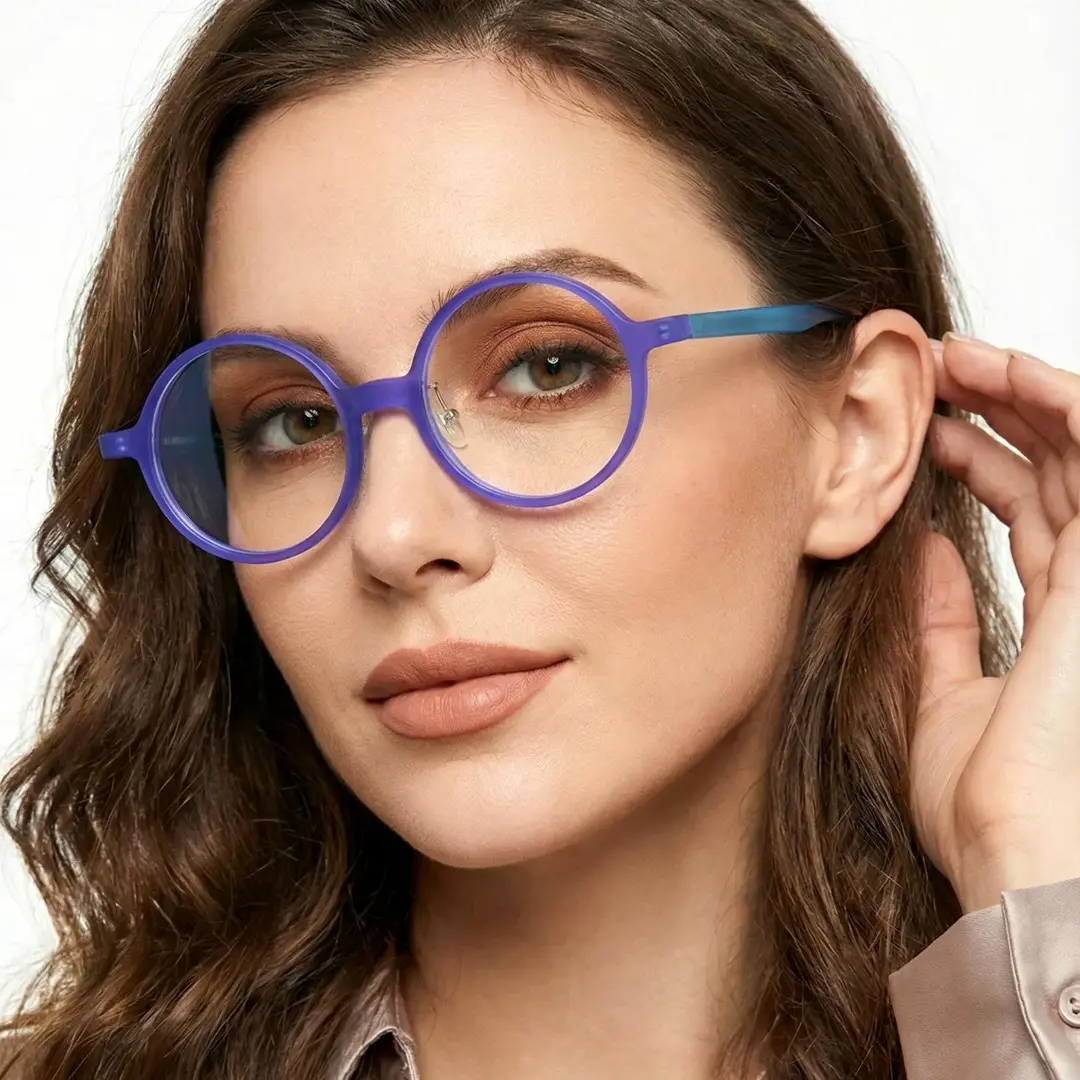 Three-quarter view of female wearing colorful purple round eyeglasses, hand in hair, neutral expression, RA0222310