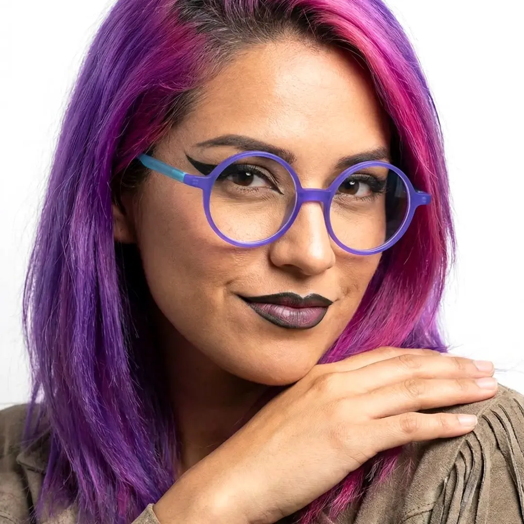 Slightly angled view of female wearing purple round eyeglasses, hand resting on her shoulder, soft smile, RA0222310