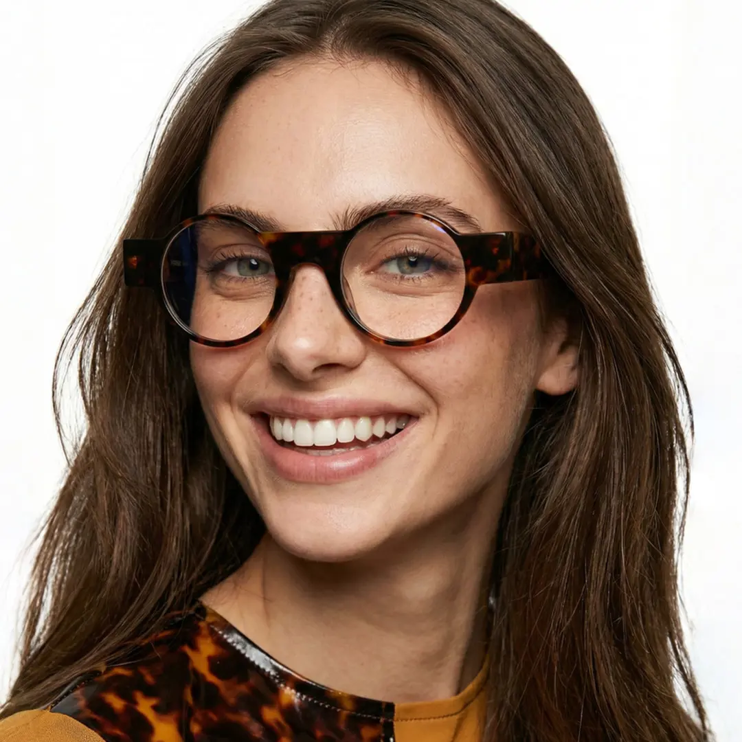 Over-the-shoulder view of female wearing tortoise round eyeglasses, smiling, RA0232404