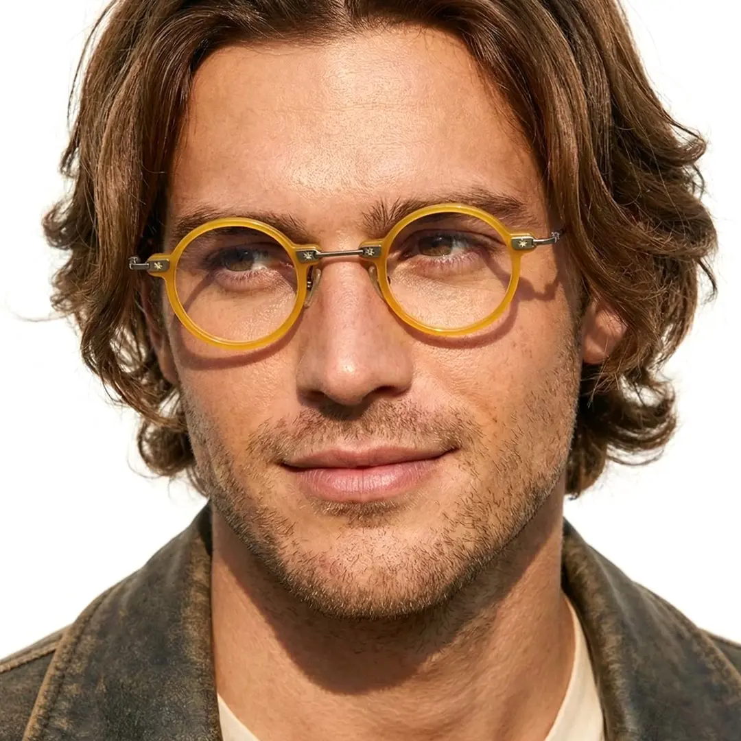 Slightly angled view of male wearing steampunk yellow round eyeglasses, soft smile, RA0282411