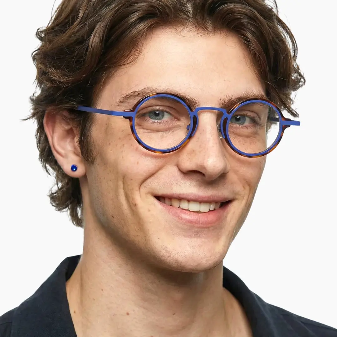 Three-quarter view of male wearing blue tortoise round eyeglasses, natural smile, RA0302402