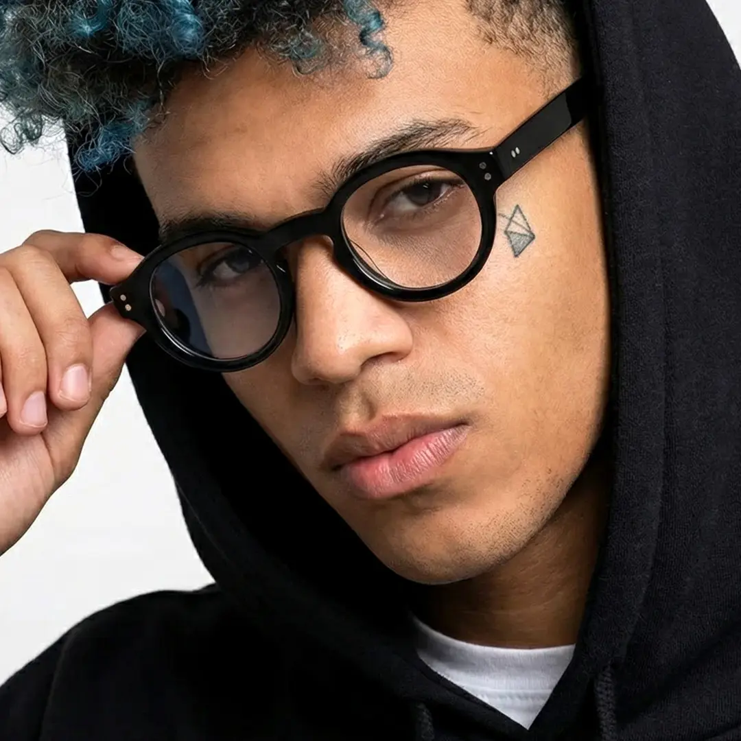 Front view of male wearing vintage black round eyeglasses, touching frame, calm expression, RA0302504