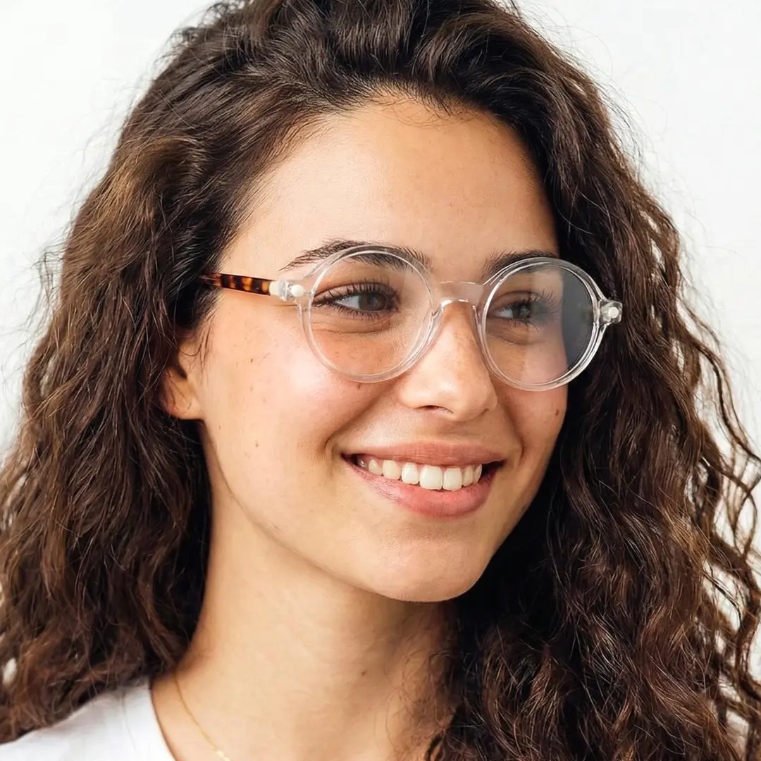 Looking away view of female wearing clear round eyeglasses, smiling, RA0312504
