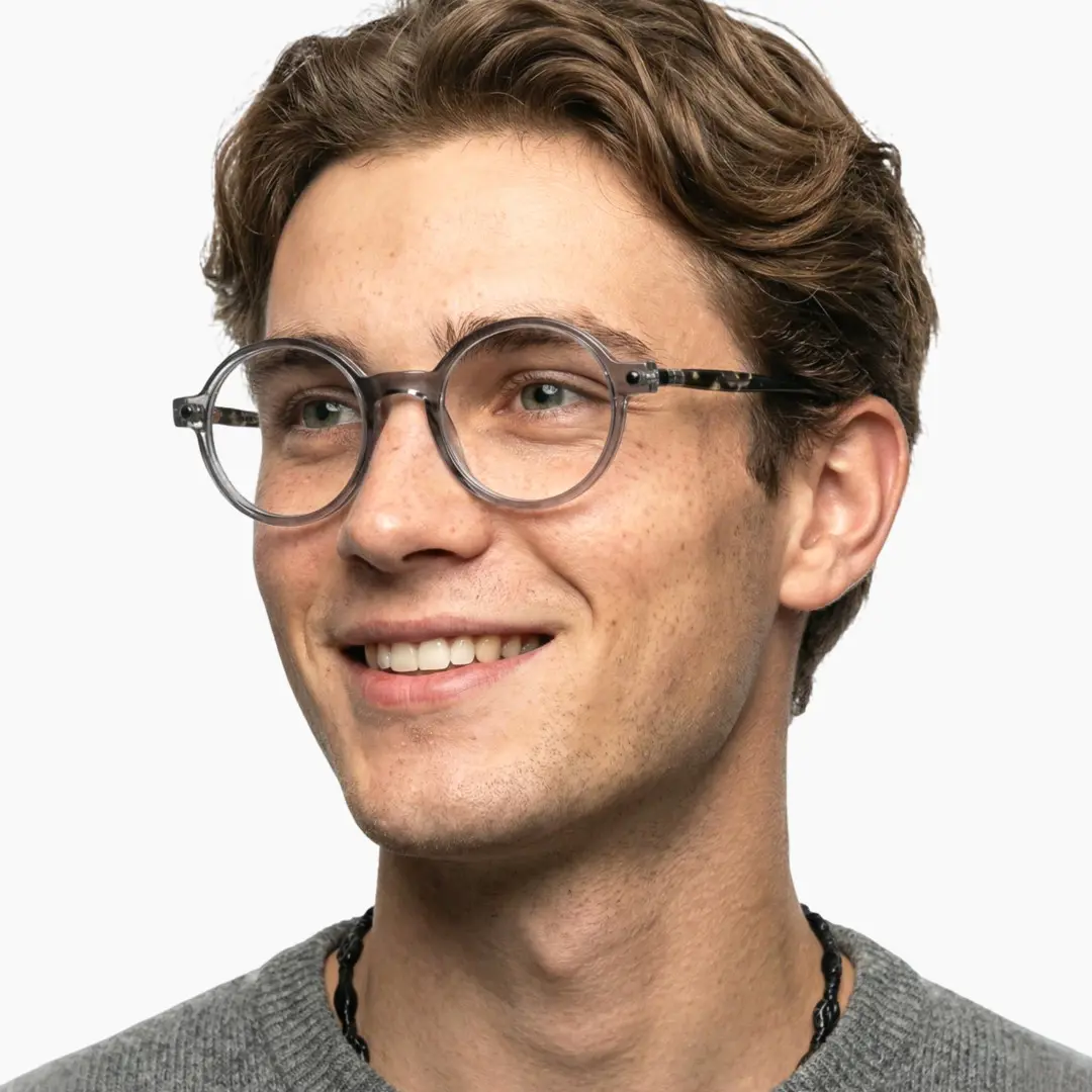 Three-quarter view of male wearing grey round eyeglasses, smiling, RA0312504