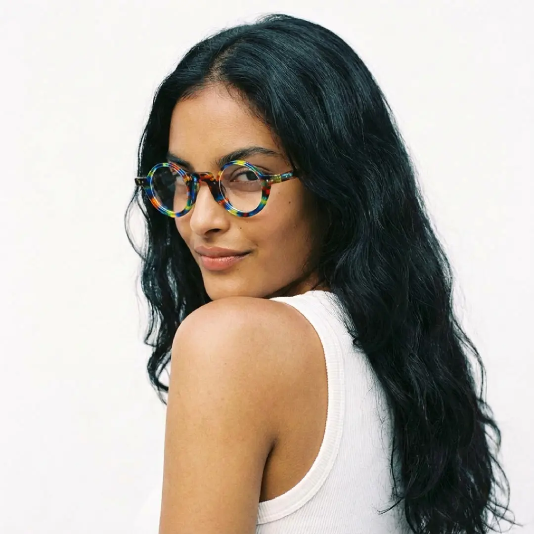 Over-the-shoulder view of female wearing multicolor round eyeglasses, natural smile, RA0322504