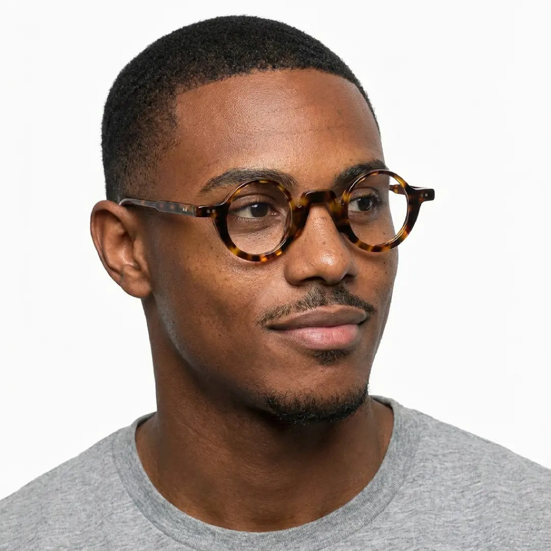 Three-quarter view of male wearing vintage tortoise round eyeglasses, friendly smile, RA0322504