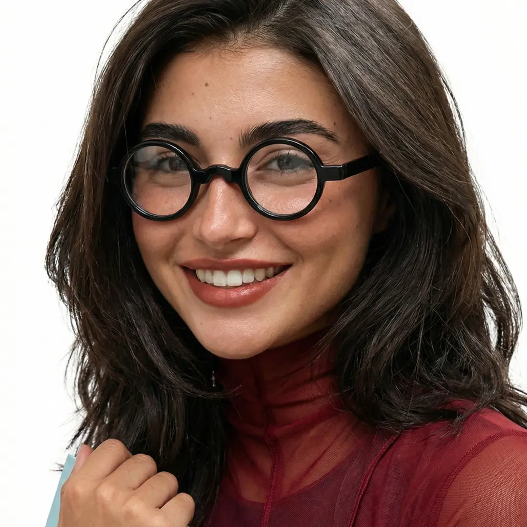 Slightly angled view of female wearing black round eyeglasses, hand in hair, smiling, RA0332507