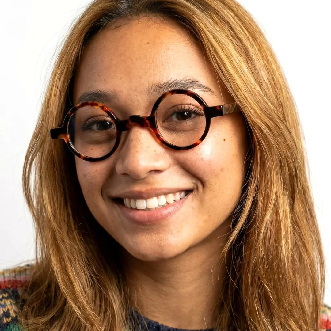 Front view of female wearing tortoise round eyeglasses, smiling, RA0332507