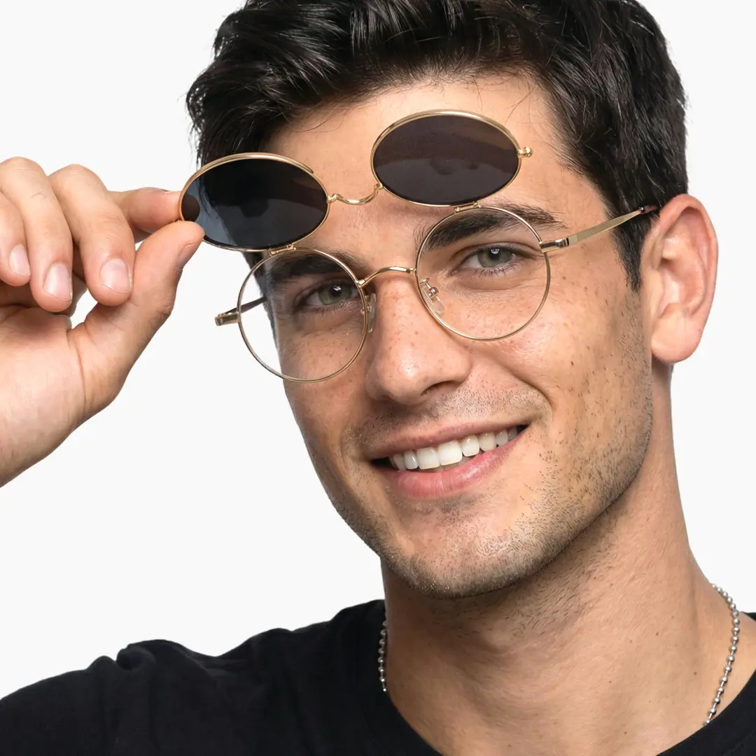 Close-up view of male wearing gold round flip-up eyeglasses, holding glasses, friendly smile, RM0042601