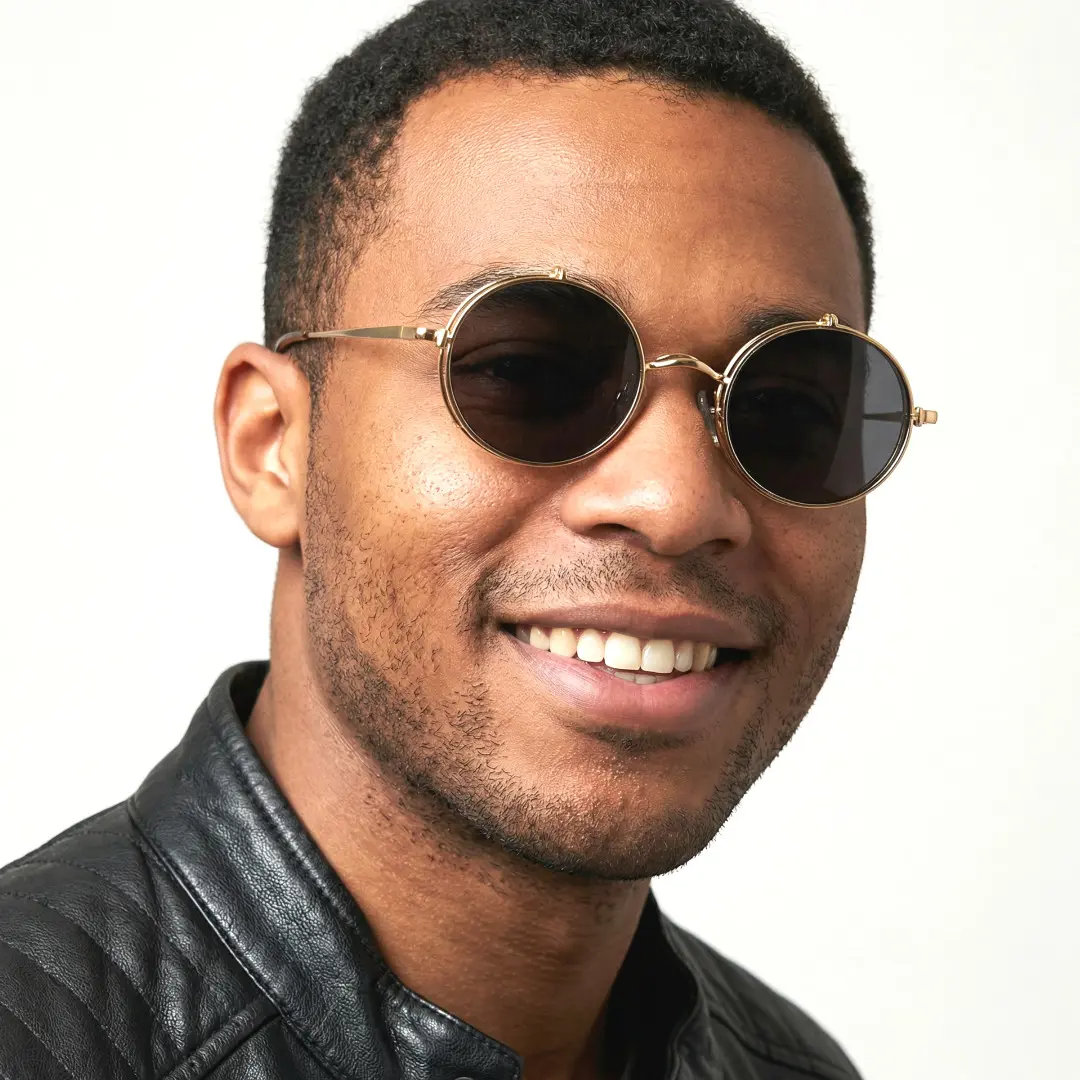 Three-quarter view of male wearing gold round flip-up eyeglasses, smiling, RM0042601