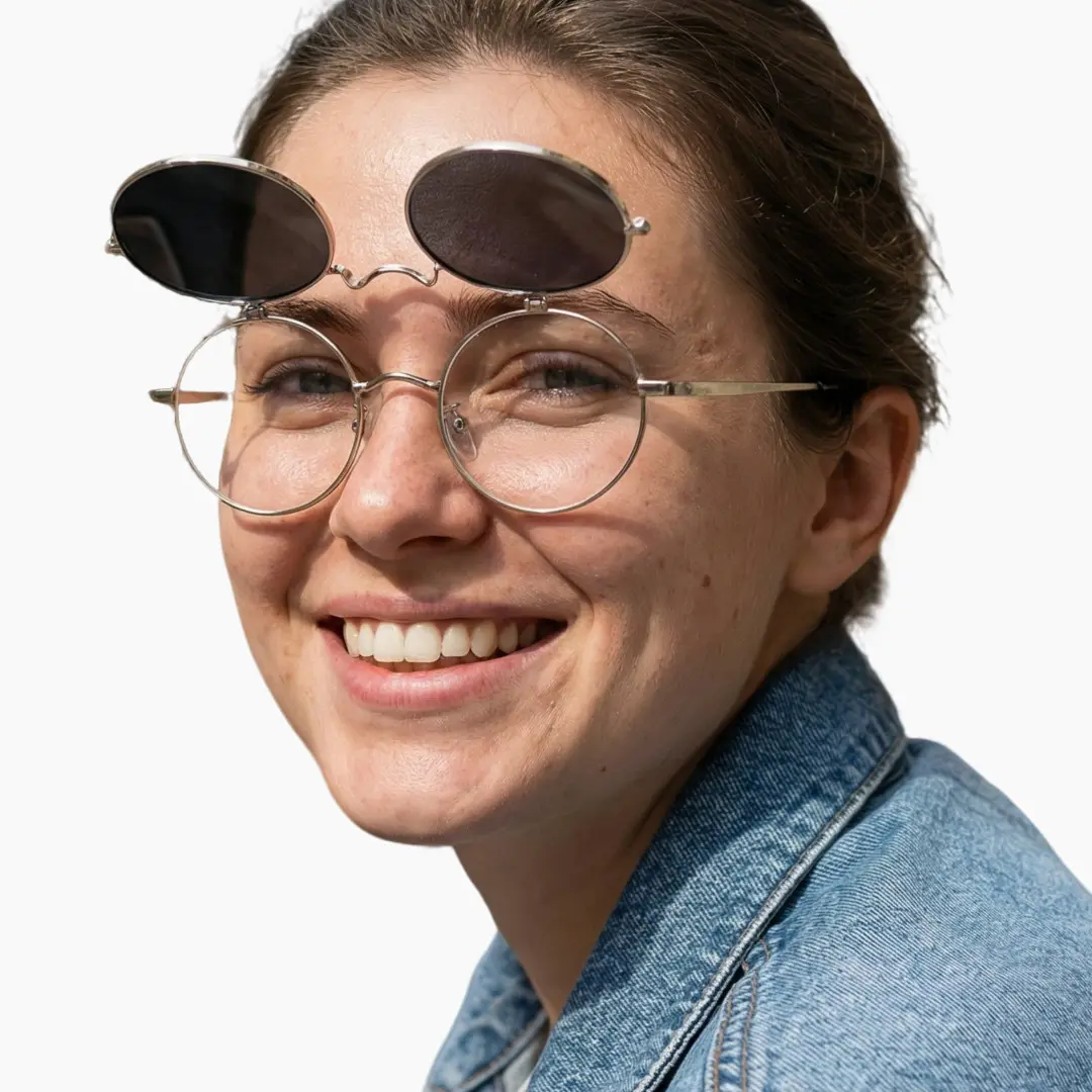 Slightly angled view of female wearing silver round flip-up eyeglasses, friendly smile, RM0042601