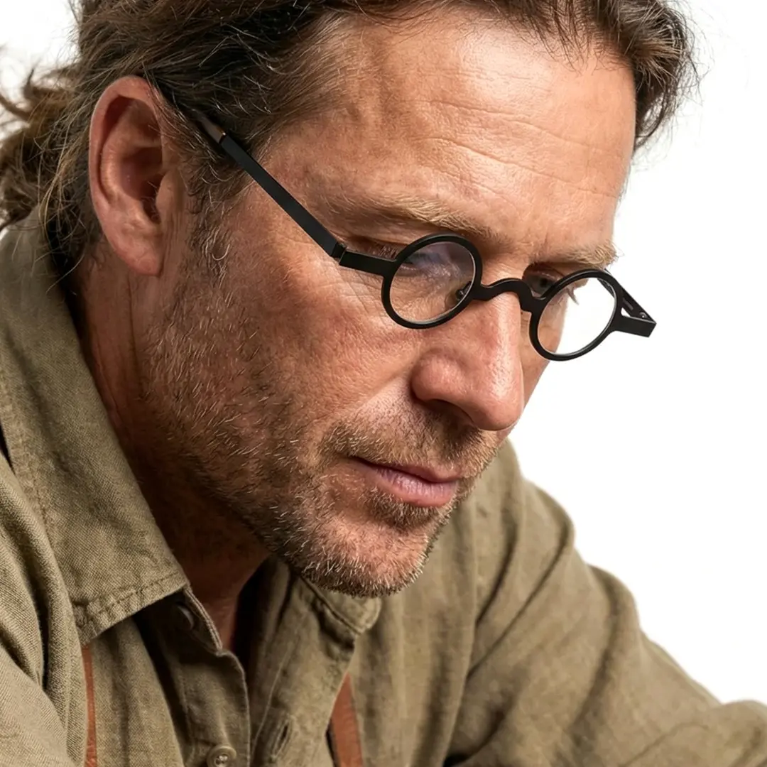 Profile view of male wearing vintage black round eyeglasses, thoughtful expression, RM0122404