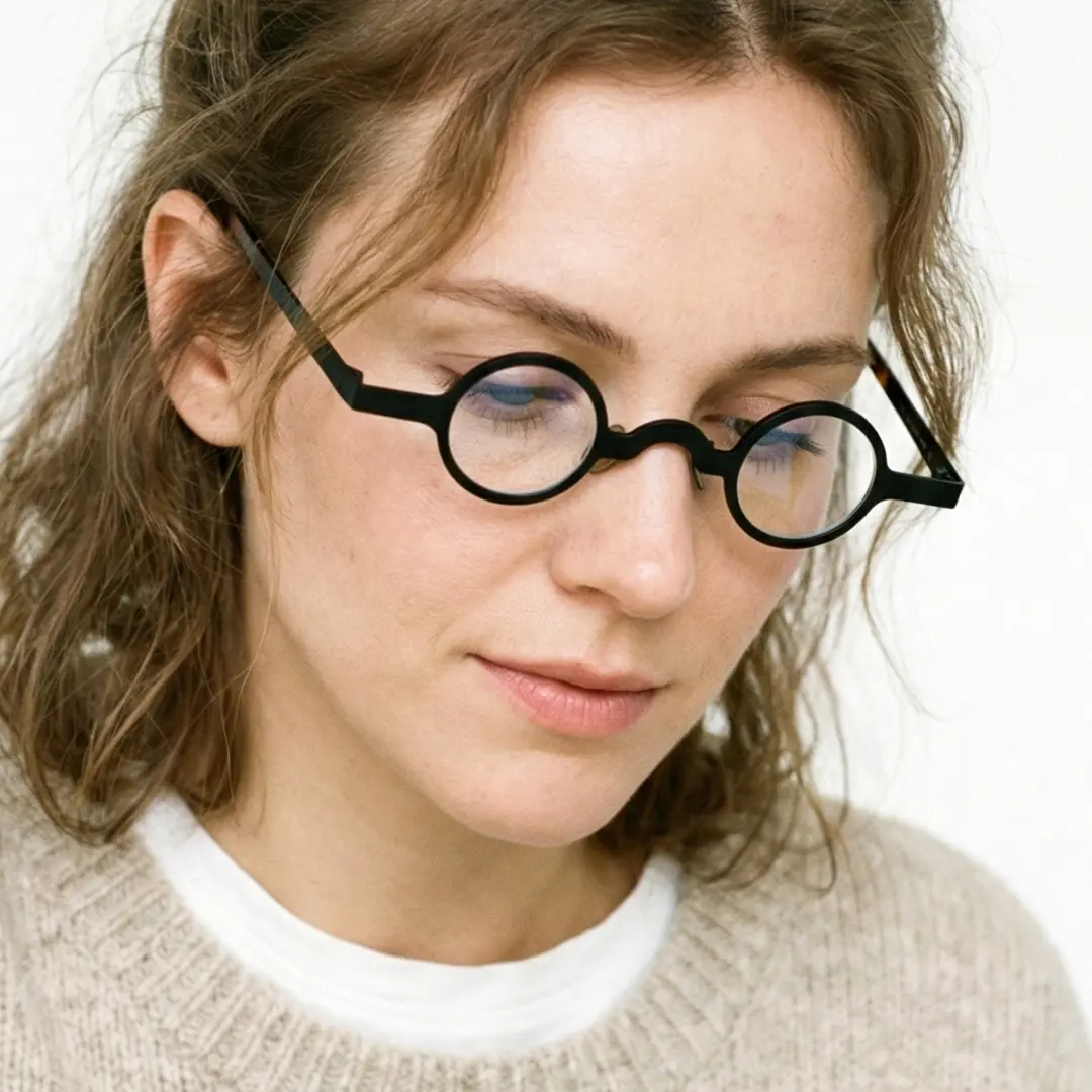 Close-up view of female wearing vintage black round eyeglasses, relaxed expression, RM0122404