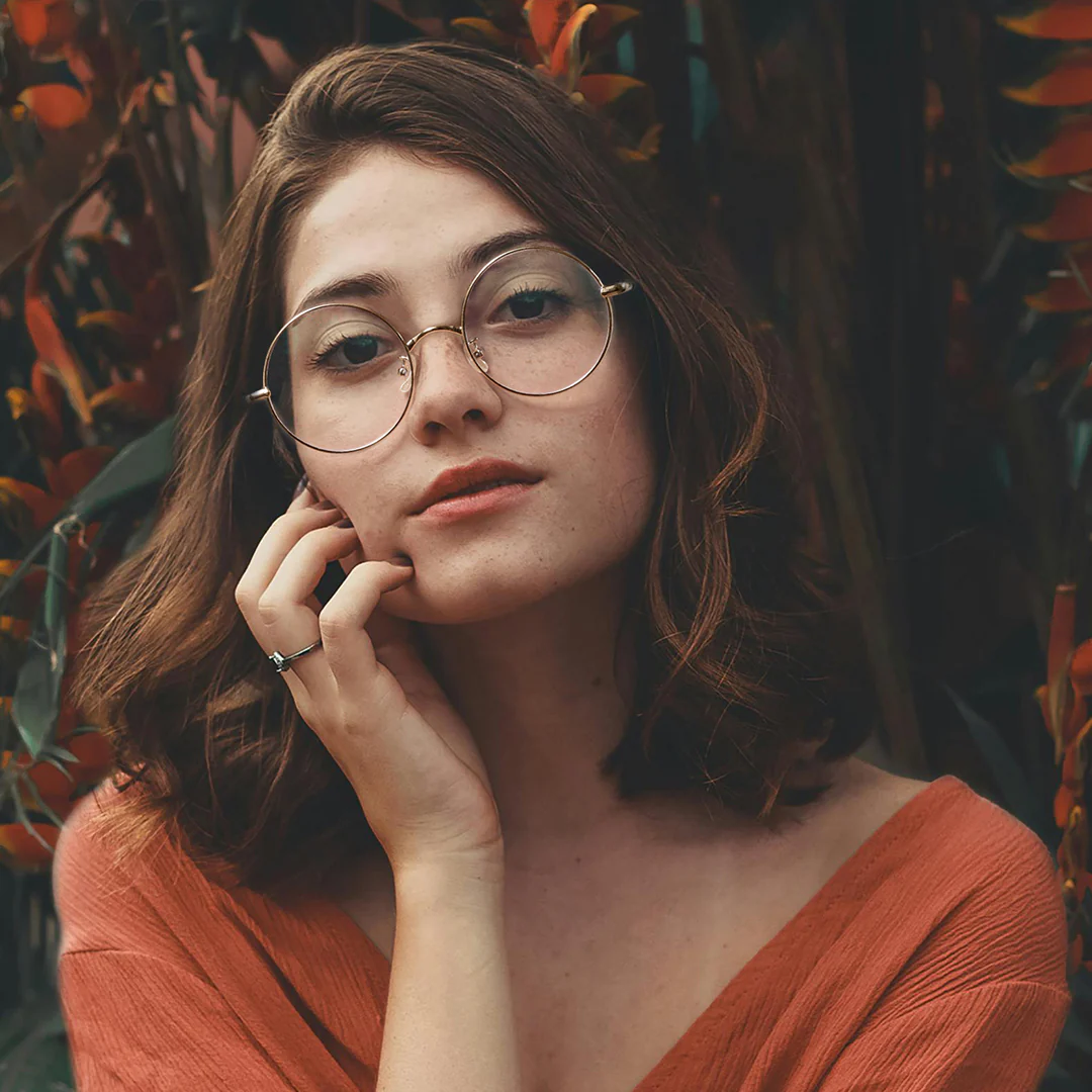 Front view of female wearing gold round eyeglasses, hand near face, natural expression, RM0302407