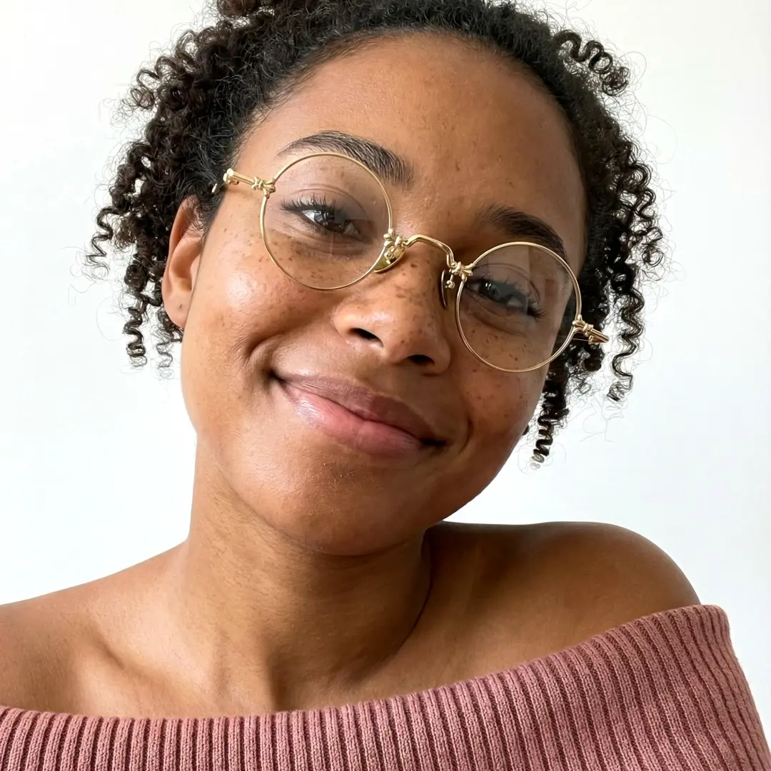 Face close-up of female wearing gold round eyeglasses, tilting head, wide smile, RM0352505