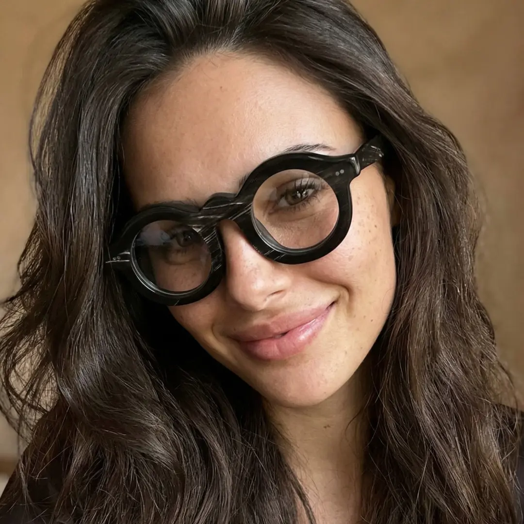 Three-quarter view of female wearing black round eyeglasses, smiling, RO0302511