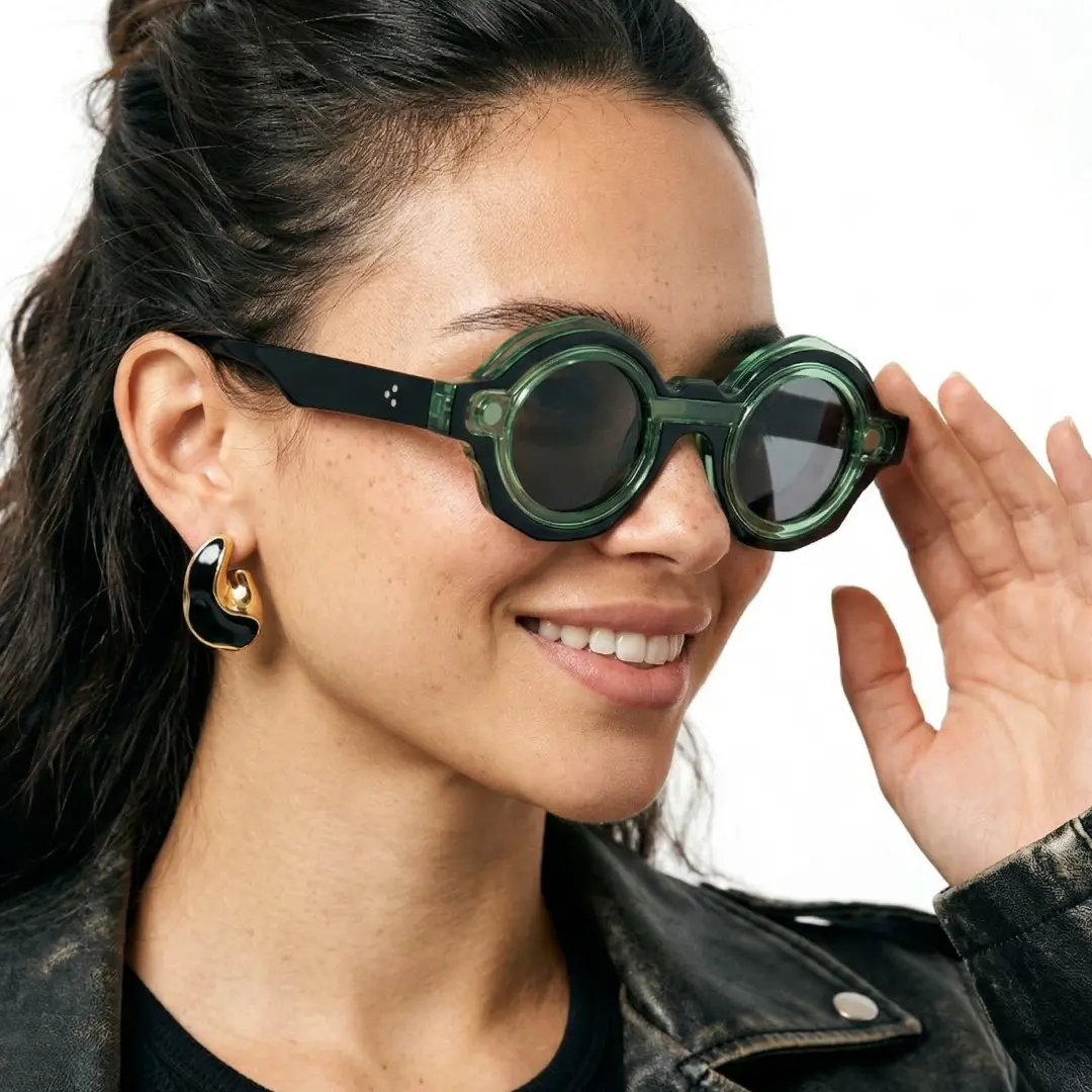 Profile view of female wearing green round eyeglasses, touching frame, smiling, RP0012604