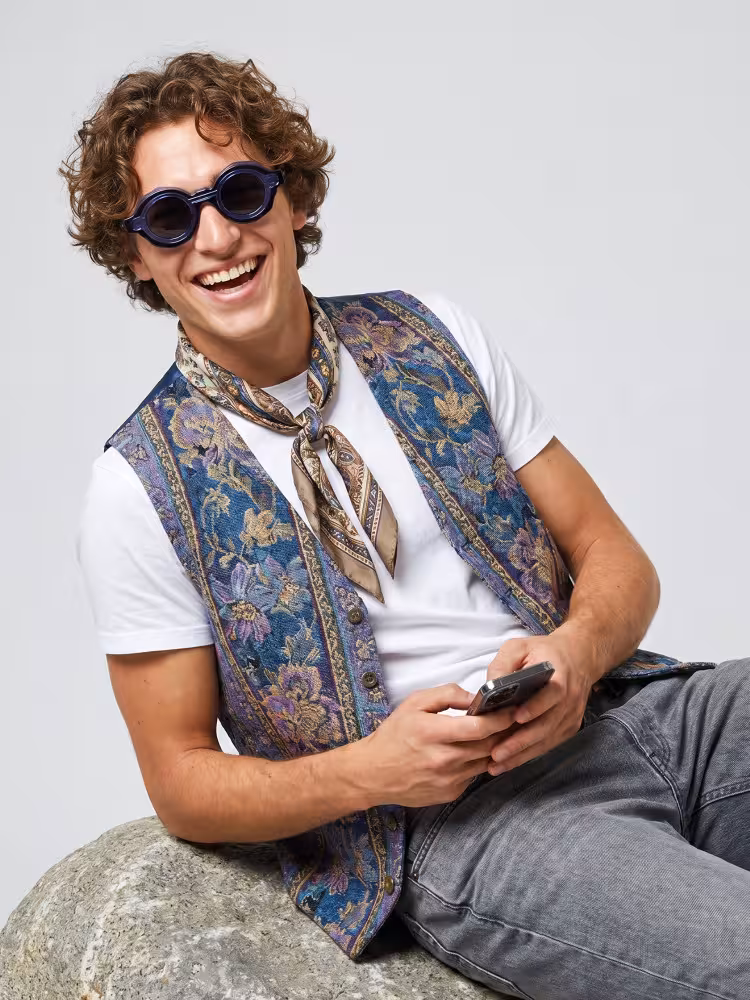 Male model wearing fashion eyewear blue round pc eyeglasses leaning on stone in plain studio background. SPU: RP0012604