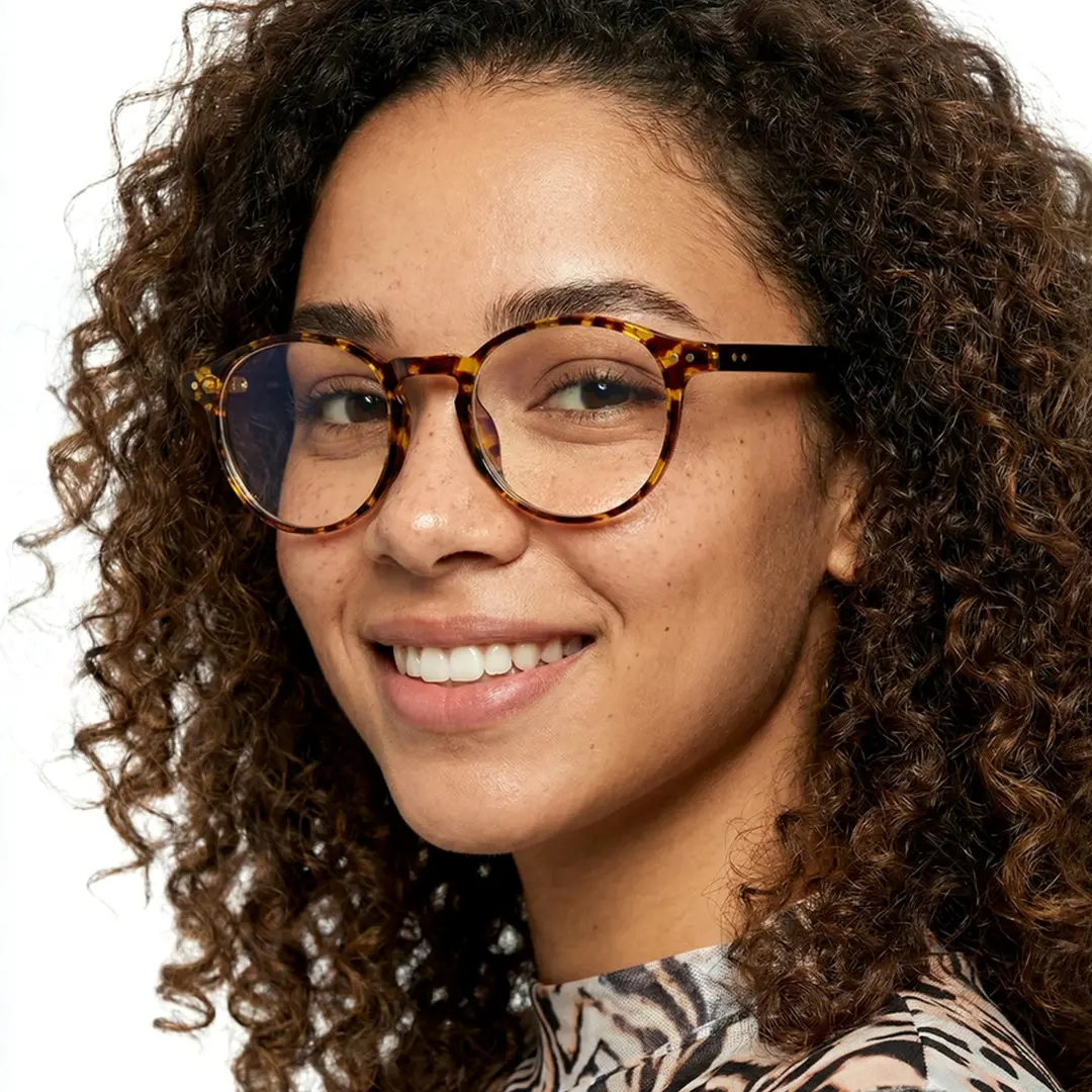 Close-up view of female wearing vintage tortoise round eyeglasses, smiling, RR0032309