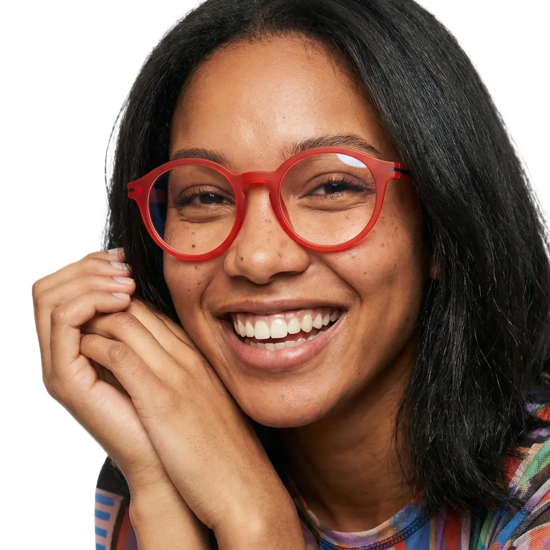 Front view of female wearing colorful red round eyeglasses, hand near face, smiling, RR0052412