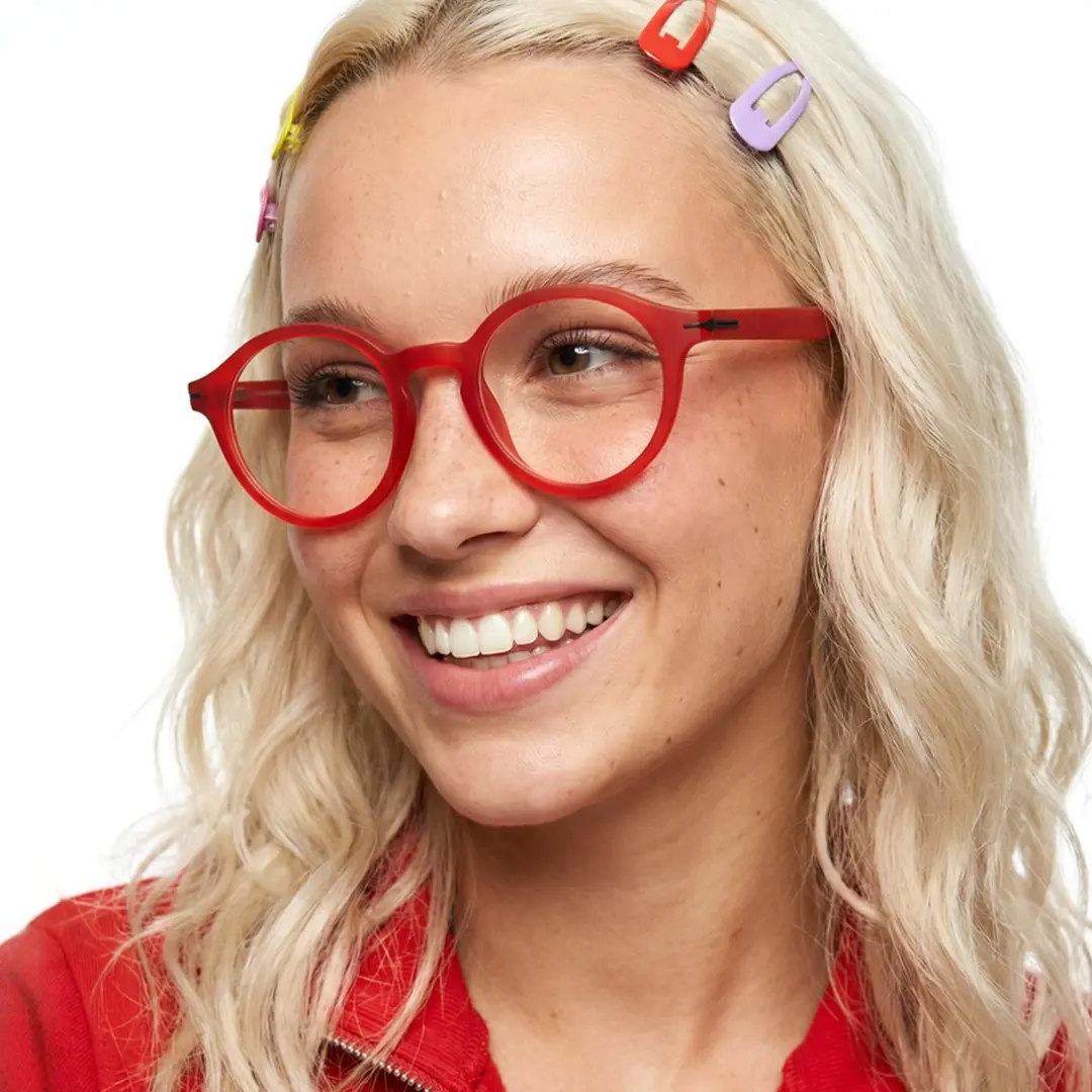 Looking away view of female wearing colorful red round eyeglasses, smiling, RR0052412