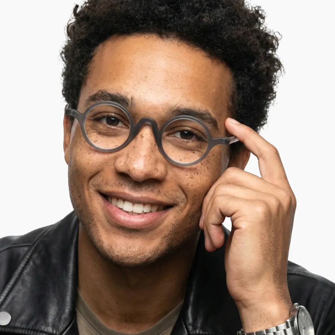 Front view of male wearing vintage grey round eyeglasses, hand near face, smiling, RR0282410