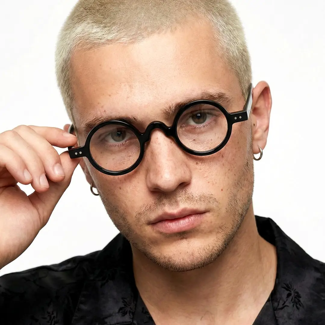 Front view of male wearing vintage black round eyeglasses, touching frame, calm expression, RR0322601