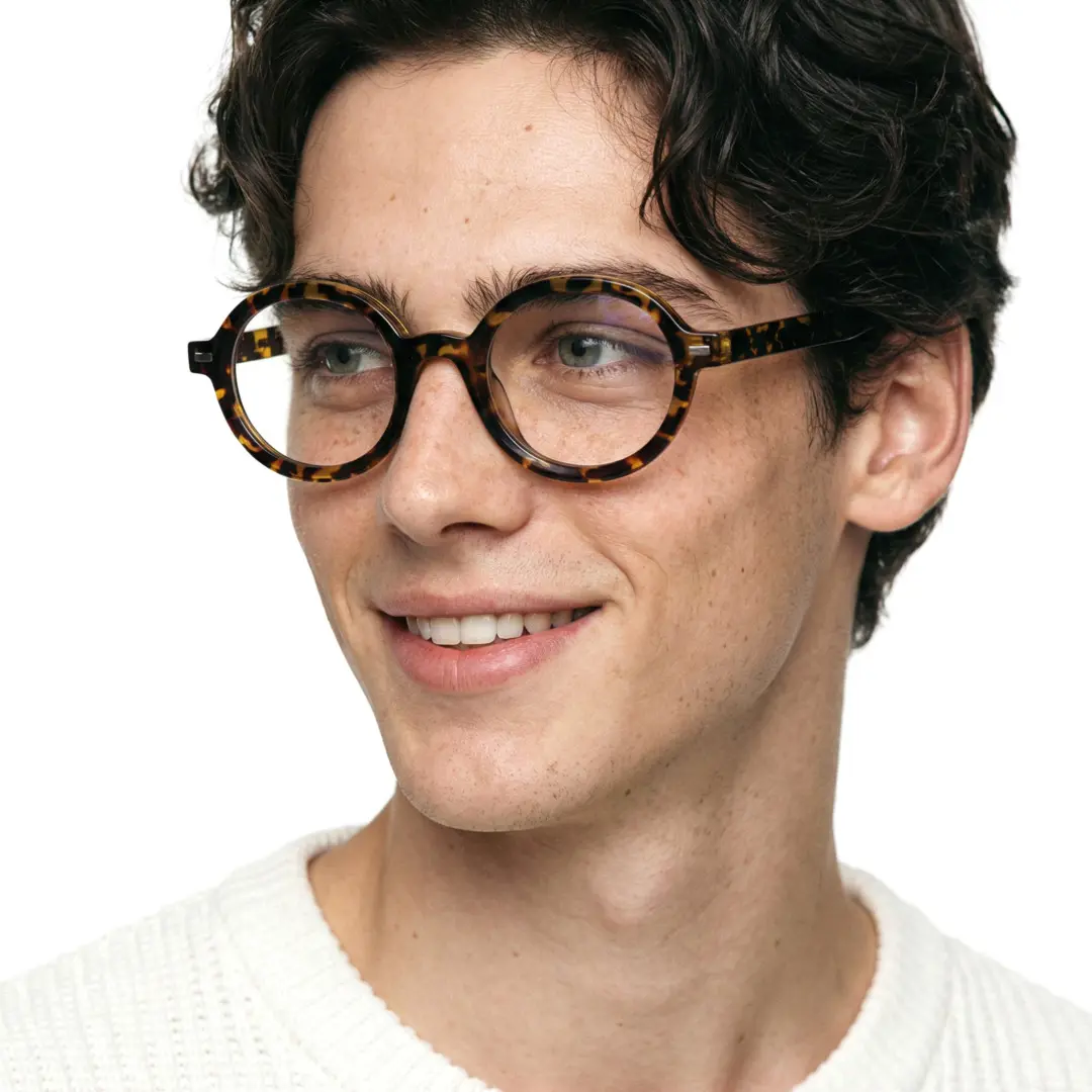 Looking away view of male wearing brown tortoise round eyeglasses, natural smile, RR0332302