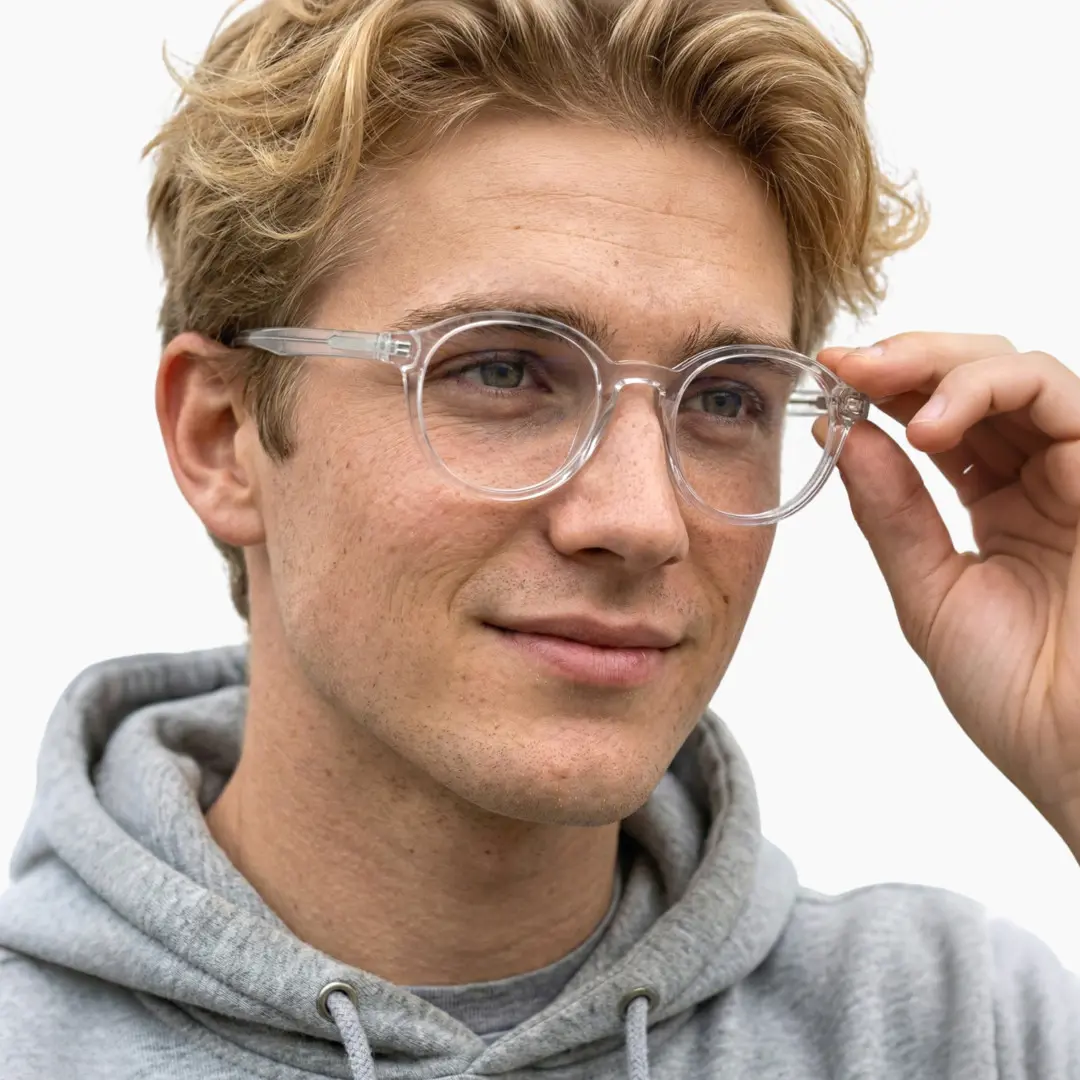 Looking away view of male wearing clear round eyeglasses, holding glasses, soft smile, RR0332302