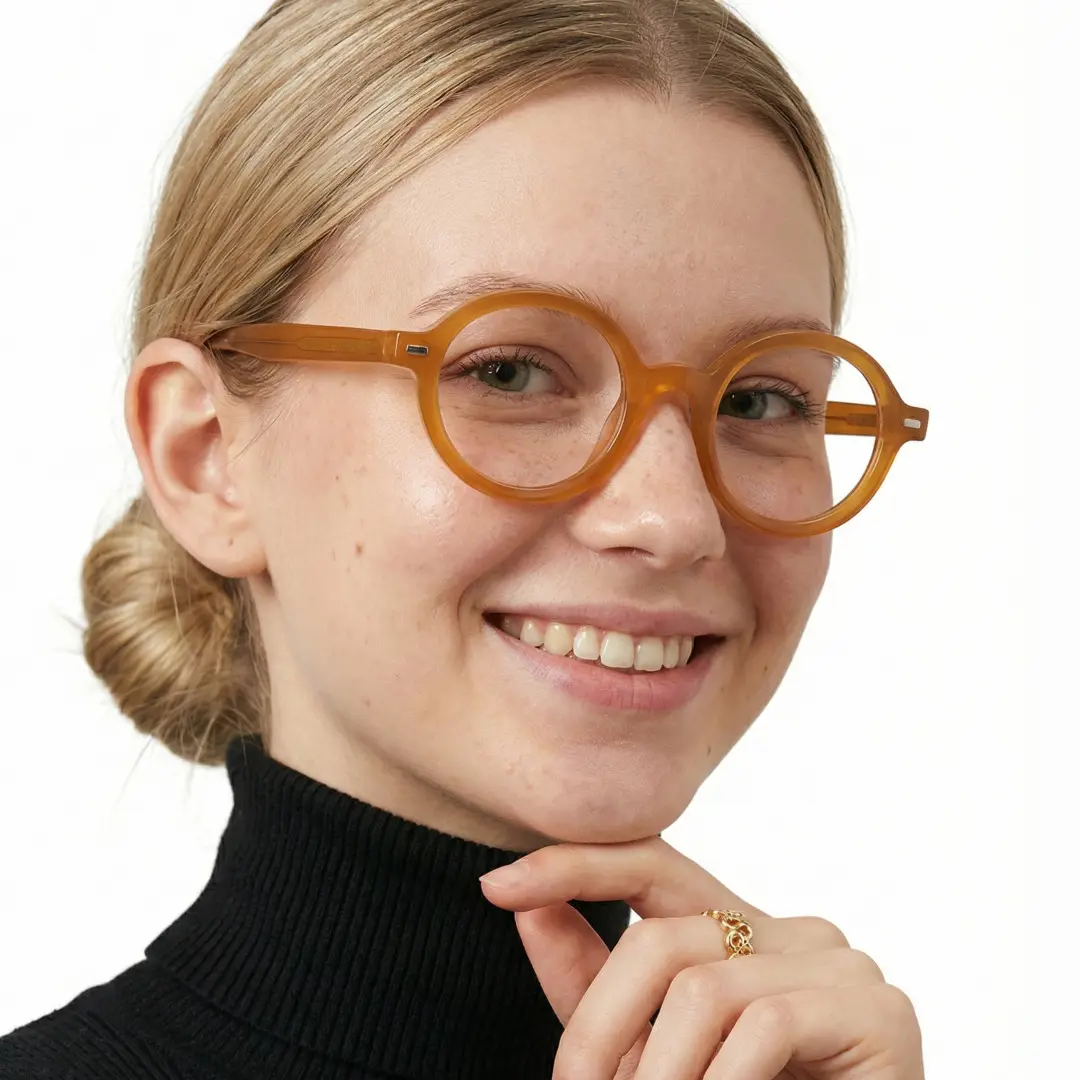 Three-quarter view of female wearing orange round eyeglasses, resting chin on hand, natural smile, RR0332302