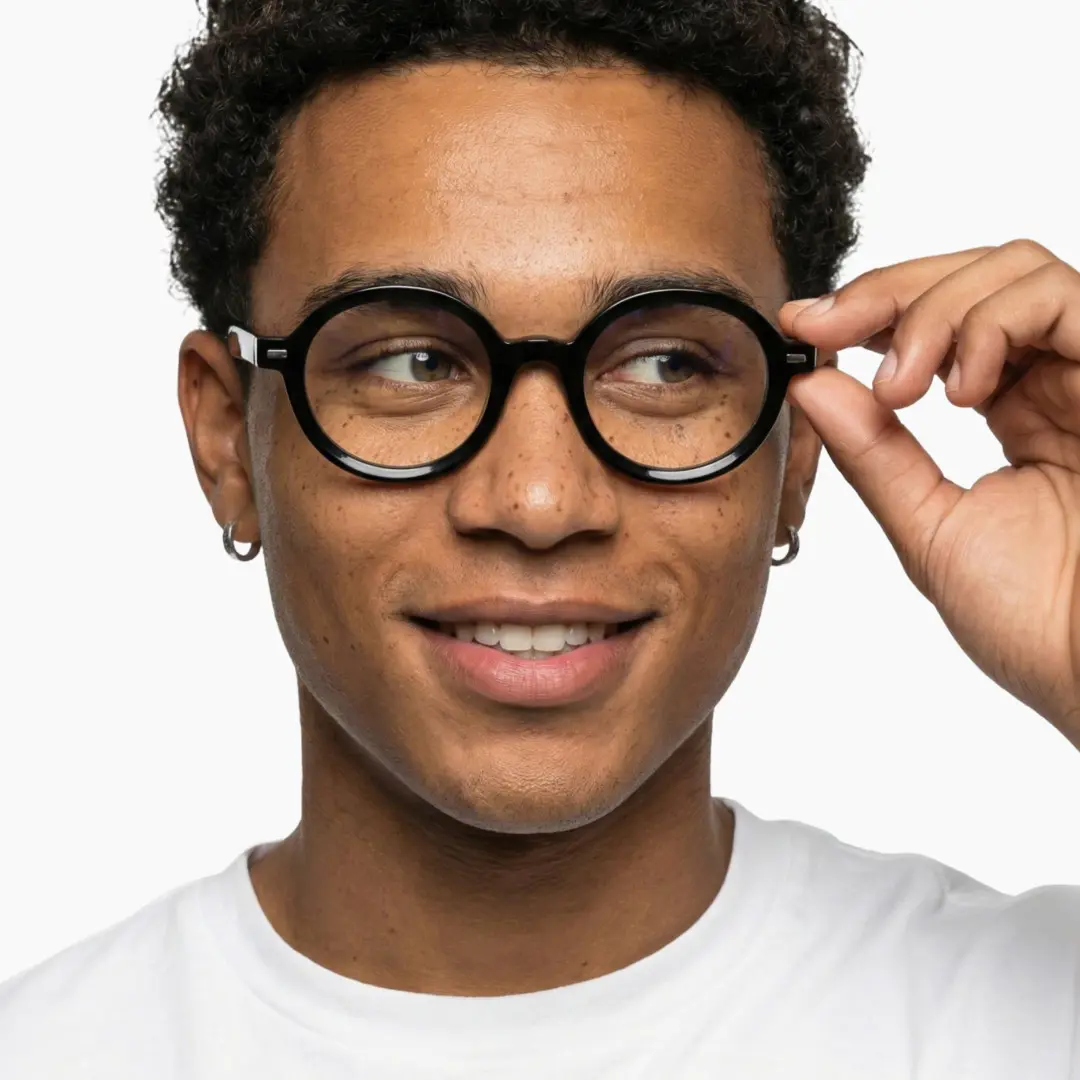 Front view of male wearing black round eyeglasses, holding glasses, natural smile, RR0332302