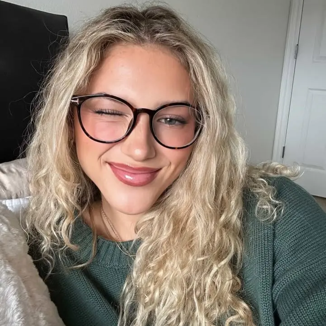 Front view of female wearing tortoise round eyeglasses, winking, soft smile, RR0352506