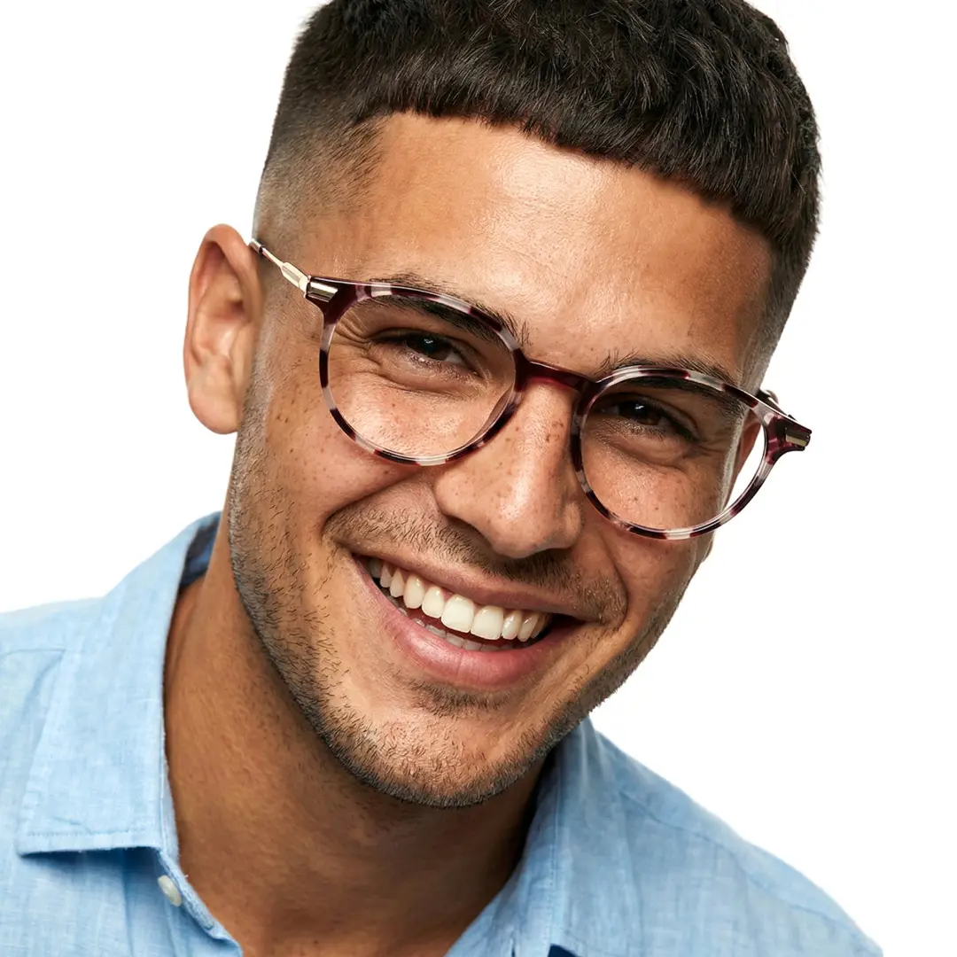 Tilted head view of male wearing tortoise round eyeglasses, smiling, RR0382504