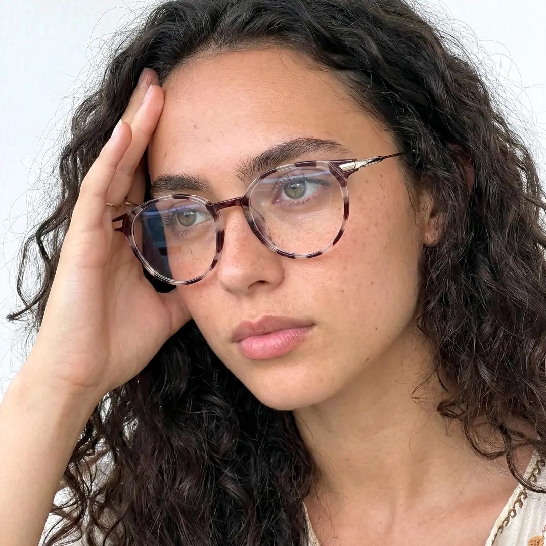 Looking away view of female wearing tortoise round eyeglasses, hand resting on forehead, calm expression, RR0382504