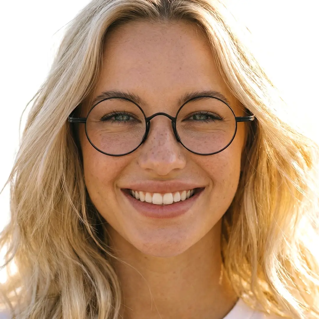 Looking straight ahead view of female wearing john lennon black round eyeglasses, natural smile, RT0172303