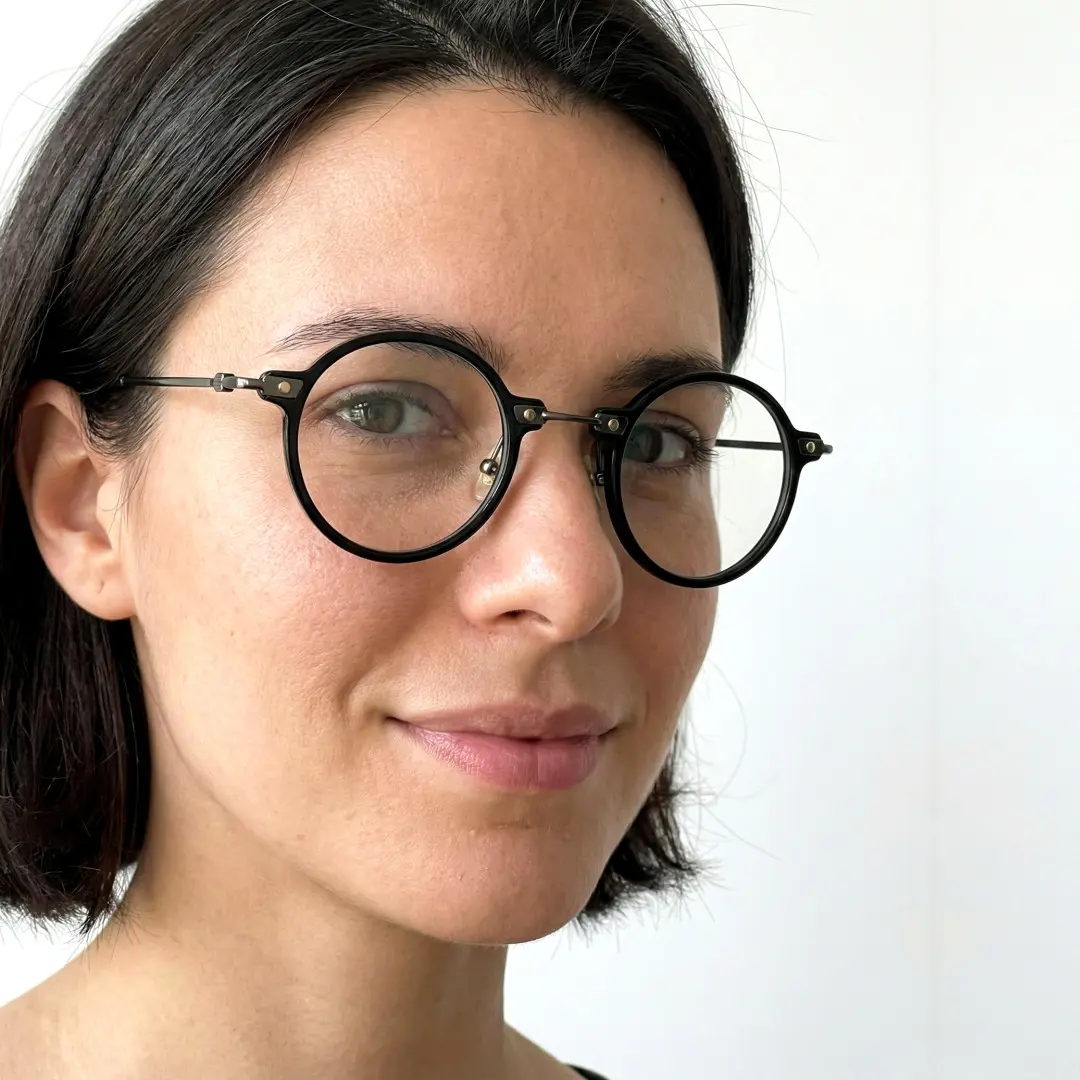 Three-quarter view of female wearing black round eyeglasses, soft smile, RT0302406