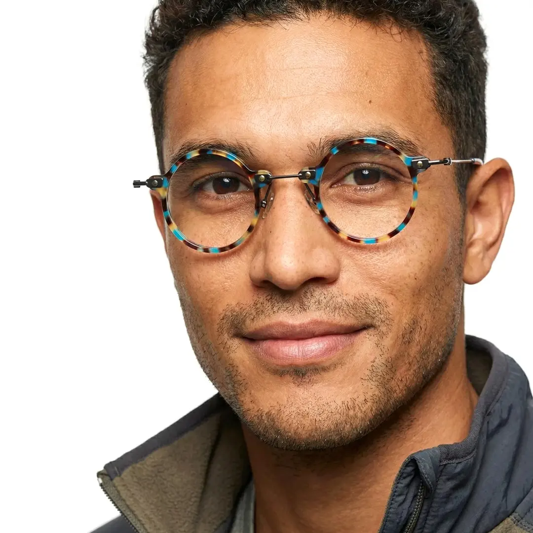 Looking straight ahead view of male wearing blue tortoise round eyeglasses, soft smile, RT0302406