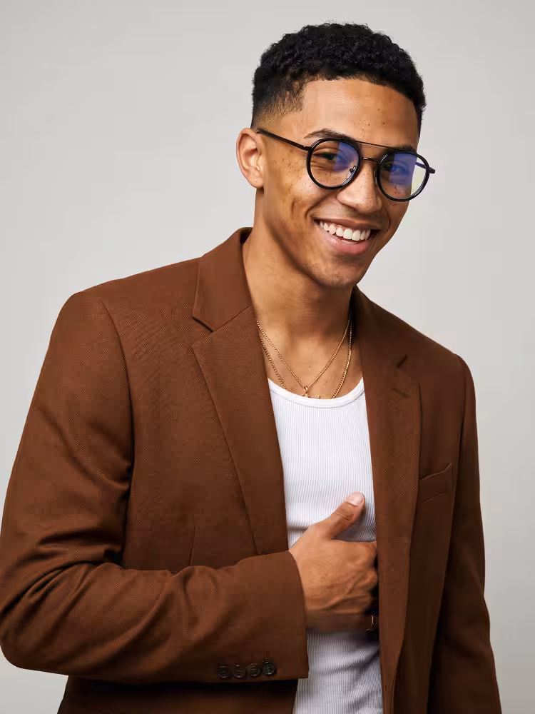 Male model wearing steampunk black round tr90 eyeglasses and a brown blazer in a studio setting. SPU: RX0202509