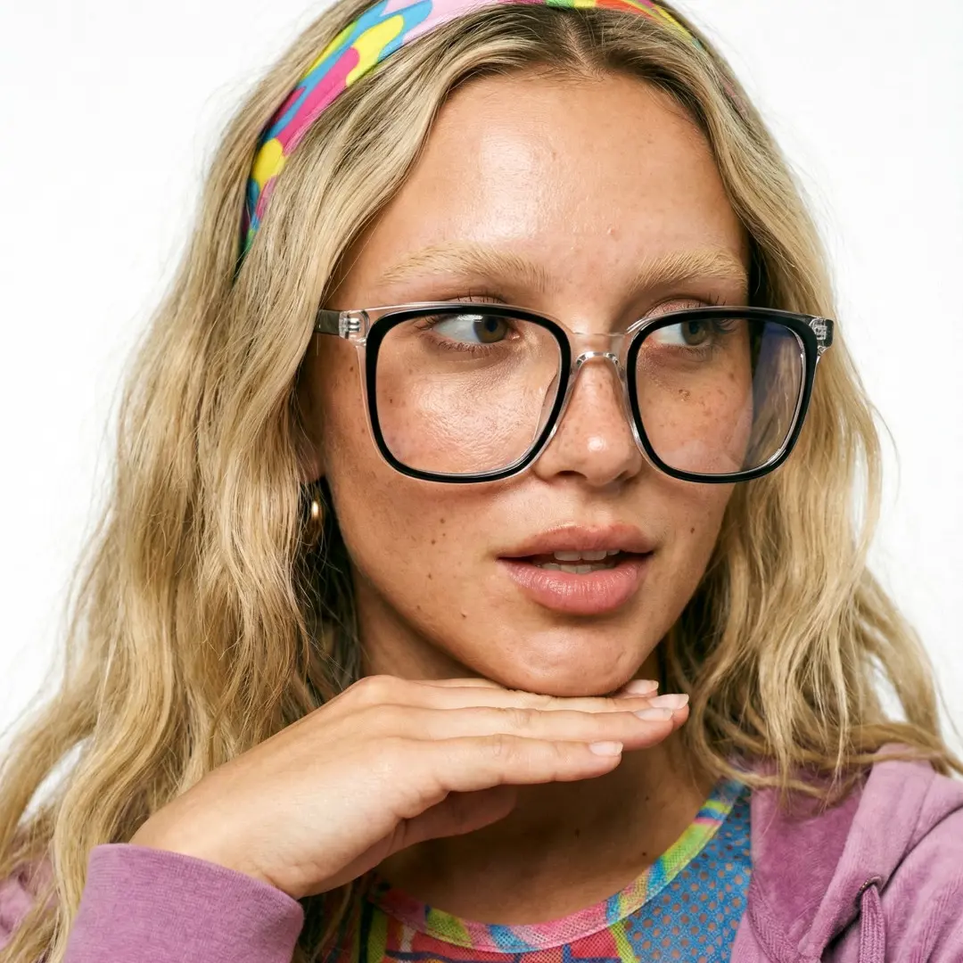 Front view of female wearing black clear square eyeglasses, resting chin on hand, smiling, SA0082305