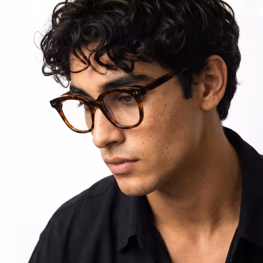 Male wearing brown tortoise square acetate eyeglasses, maintaining a neutral expression while looking away. SPU: SA0102401
