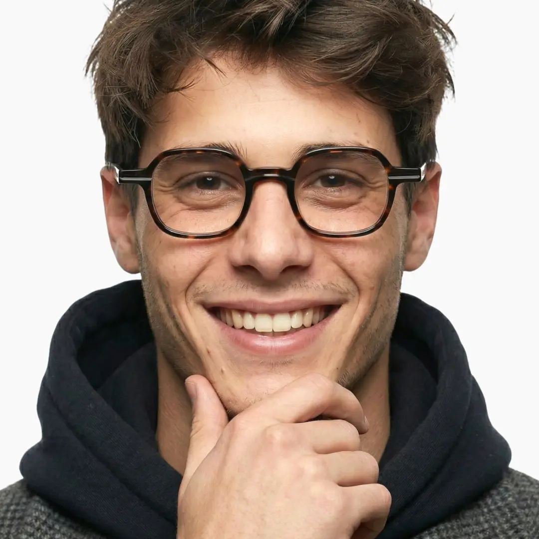 Looking straight ahead view of male wearing vintage tortoise square eyeglasses, hand touching chin, friendly smile, SA0112302