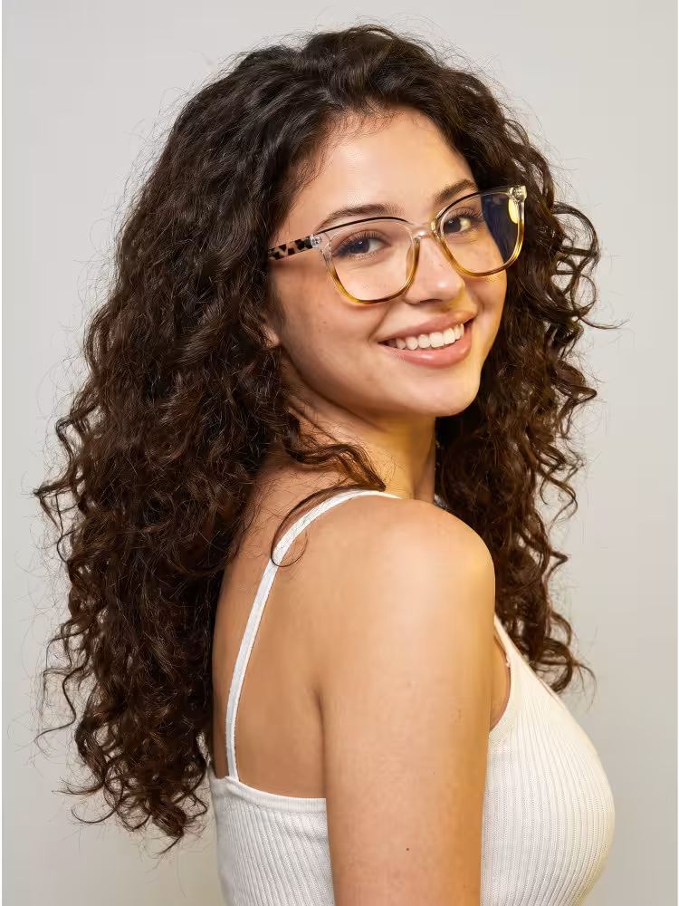 Female model wearing colorful blue tortoise square acetate eyeglasses in a white camisole top smiling over her shoulder against a plain grey studio background. SPU: SA0382605